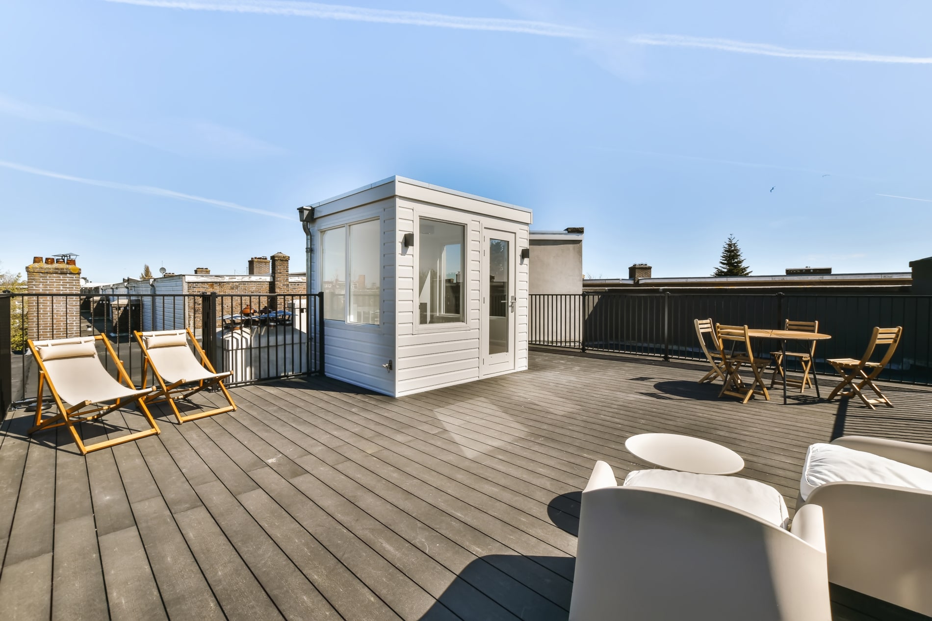 A rooftop deck with chairs and a small shed on